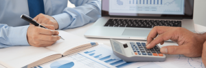 Manos revisando reportes contables con calculadora – ERP para contabilidad